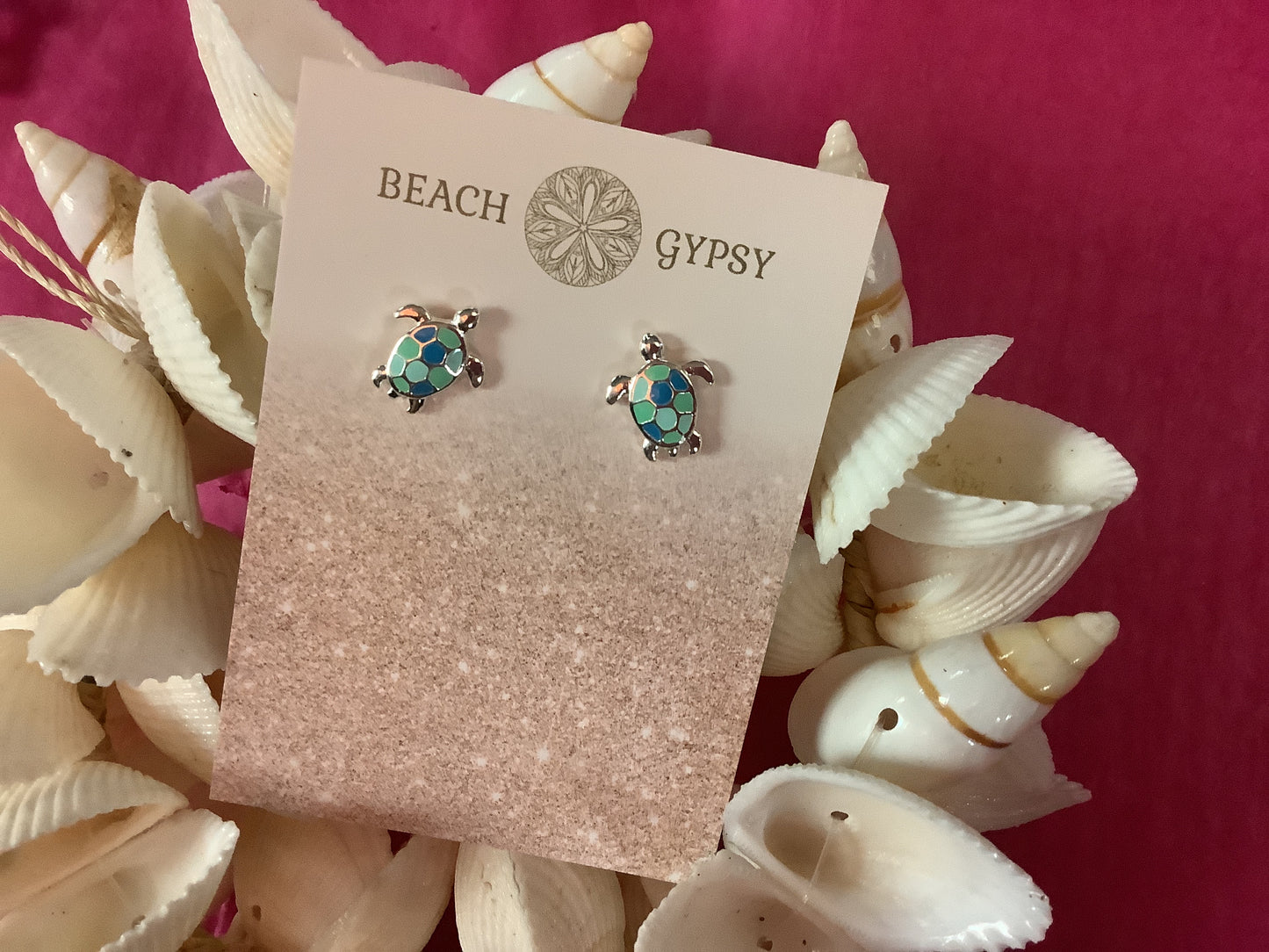 Tortoiseshell turtle earrings on a 'Beach Gypsy' branded card with seashells in the background.