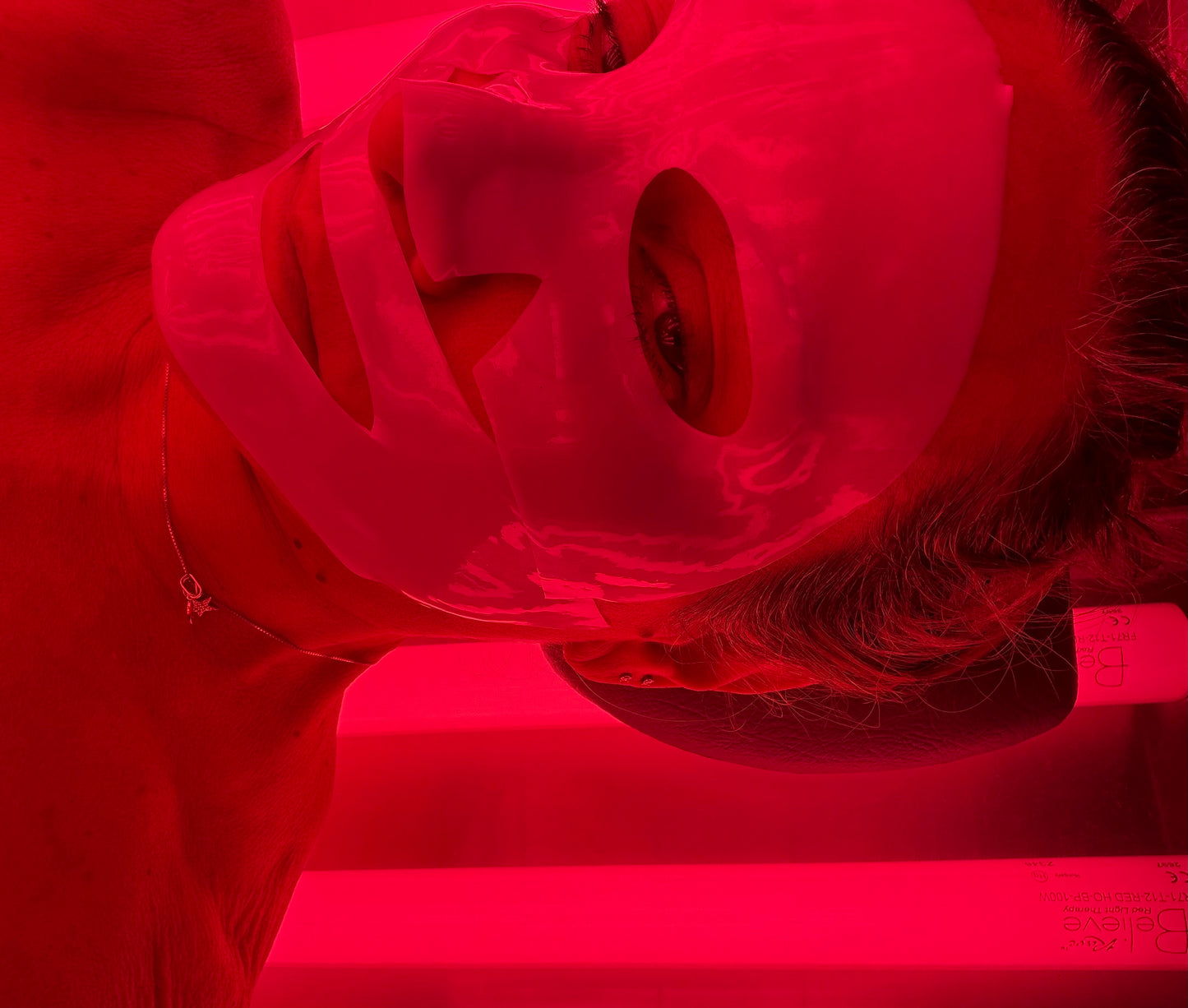 Woman relaxing with a collagen enhancing mask in a Lay-down red light therapy bed at Beach Gypsy in Berlin, MD near Ocean City, MD
