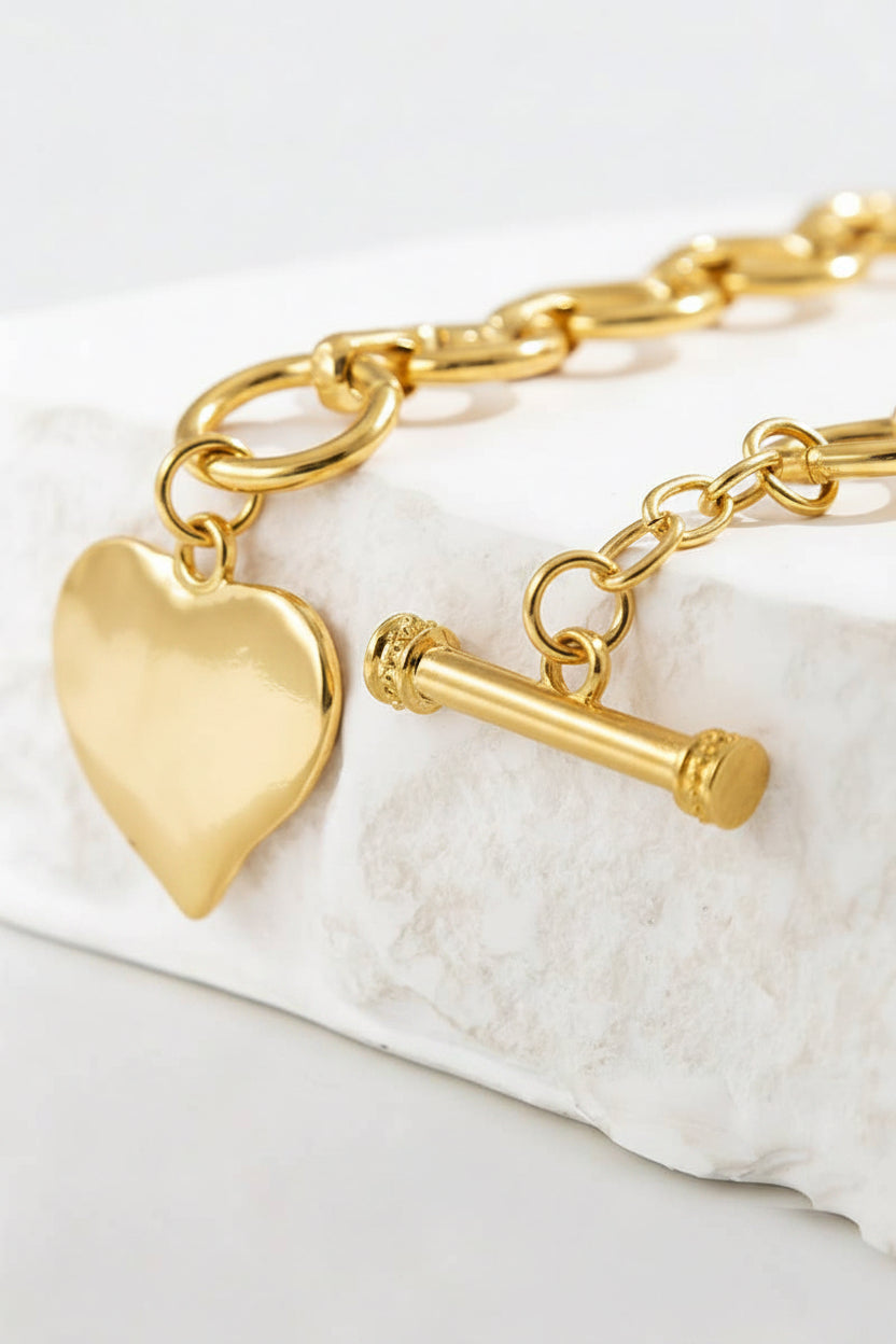 Gold necklace with heart charm on a white background