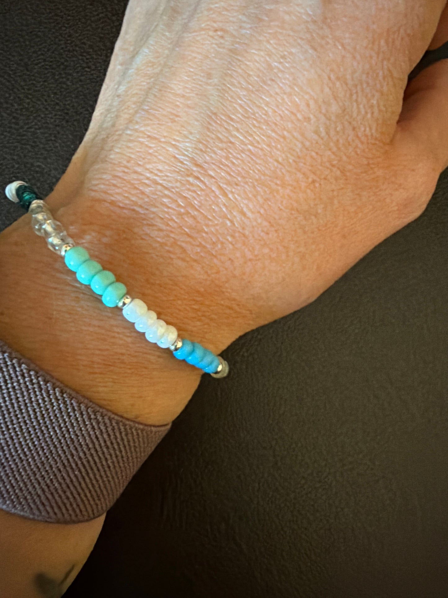 Close-up of a wrist wearing a beaded bracelet with a dark background