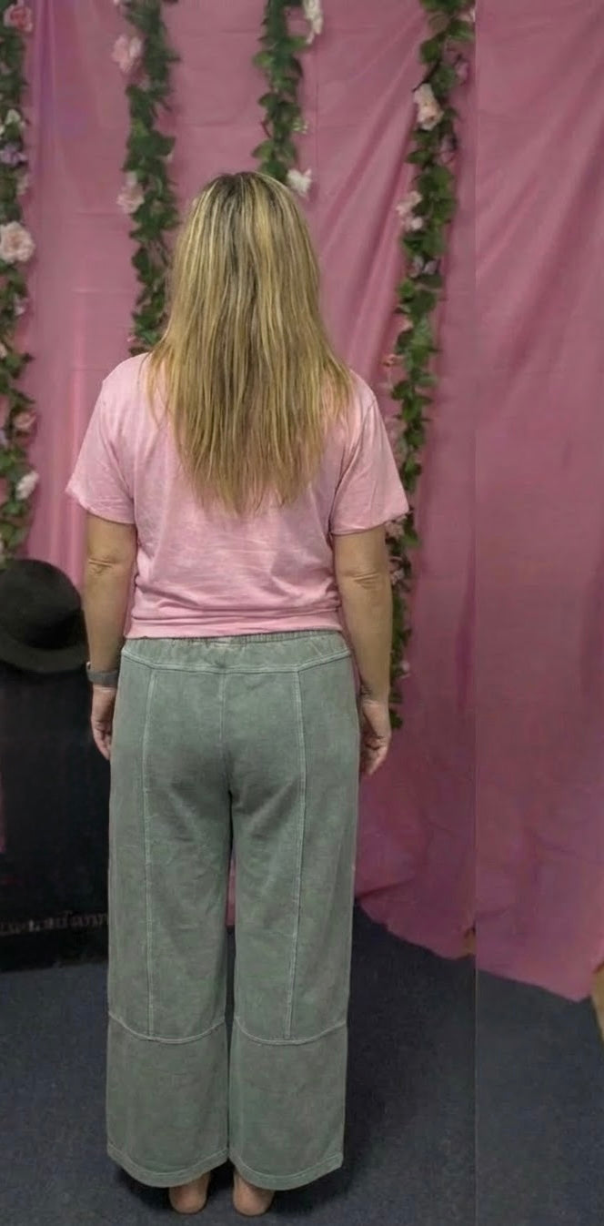 Person wearing a pink shirt and light green pants standing in front of a pink floral backdrop