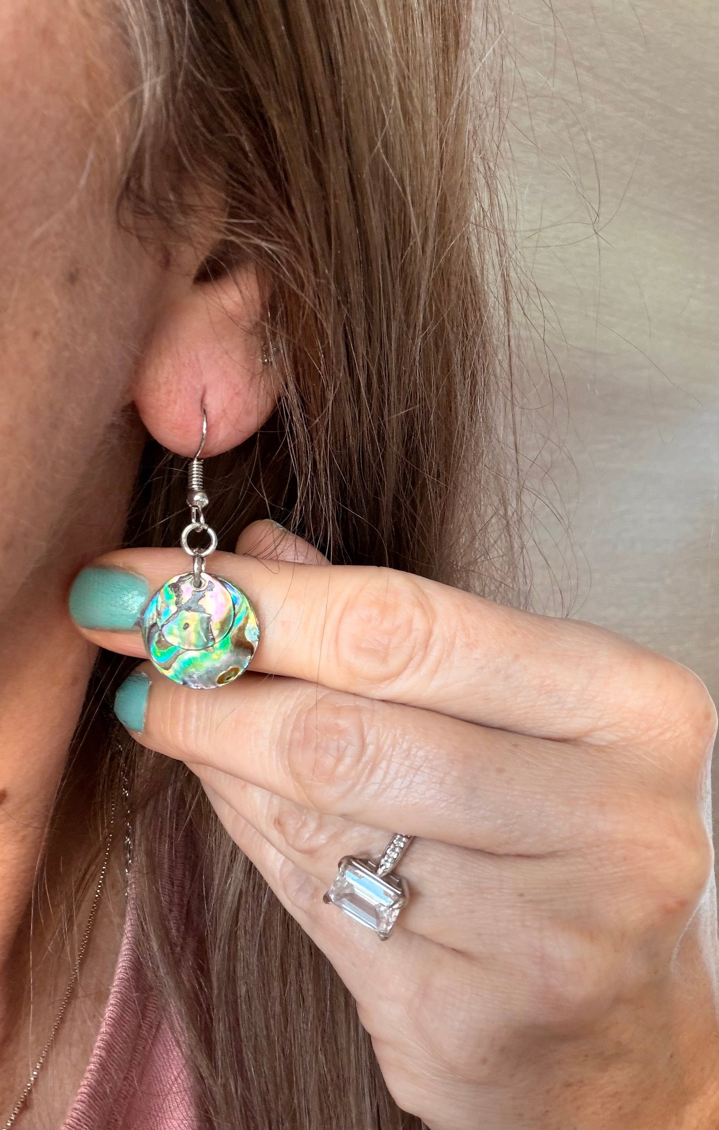 Close-up of a person wearing a colorful earring with a neutral background