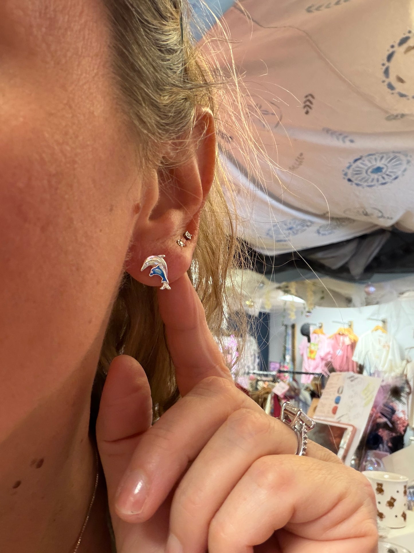 Close-up of a person wearing a dolphin-shaped earrings.
