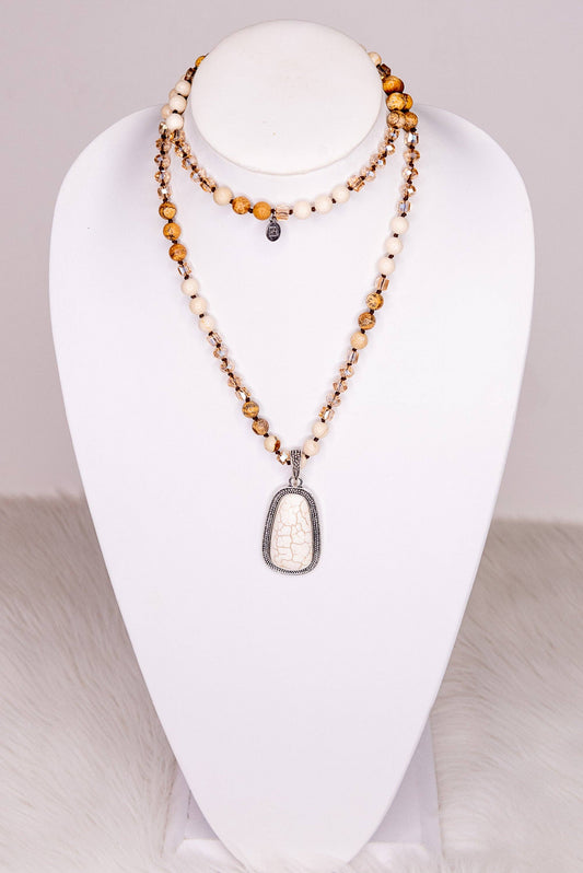 Necklace with a large white pendant on a white mannequin bust against a neutral background