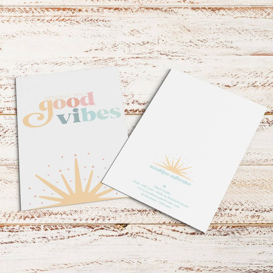Two greeting cards on a wooden surface with 'good vibes' text.