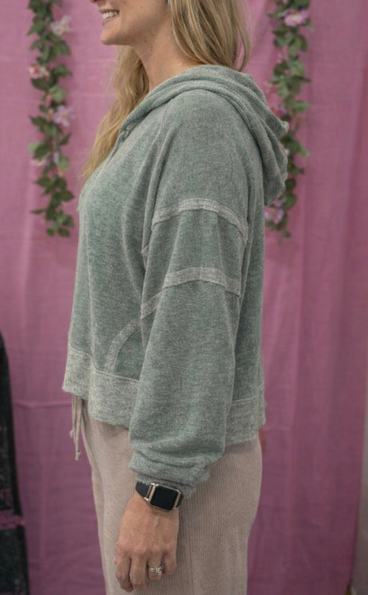 Person wearing a green hoodie with a pink background