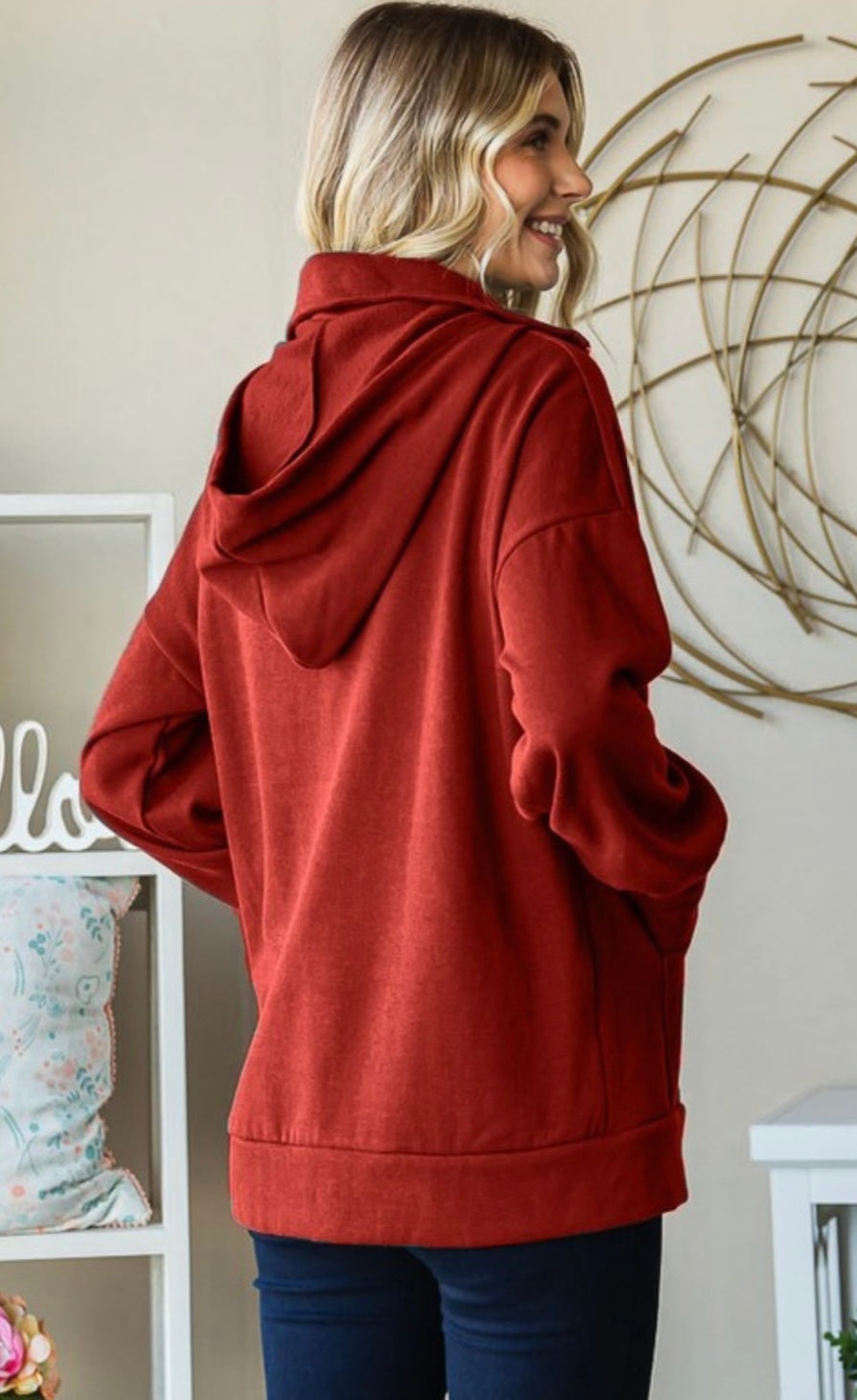 Person wearing a red hoodie in a room with decorative elements.