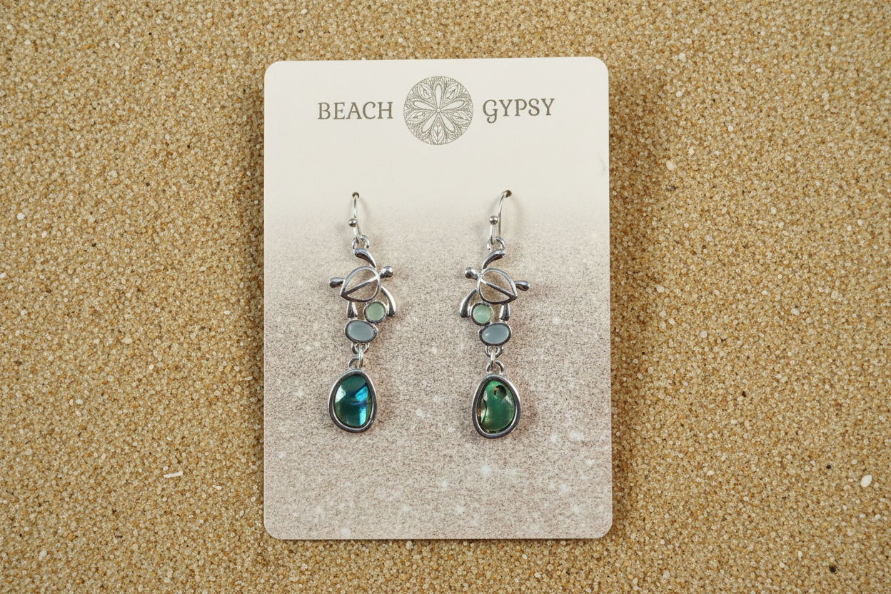 Abalone and turtle dangle earrings in a Beach Gypsy branded card on beach