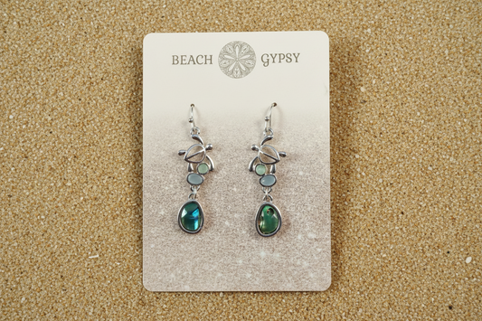 Abalone and turtle dangle earrings in a Beach Gypsy branded card on beach