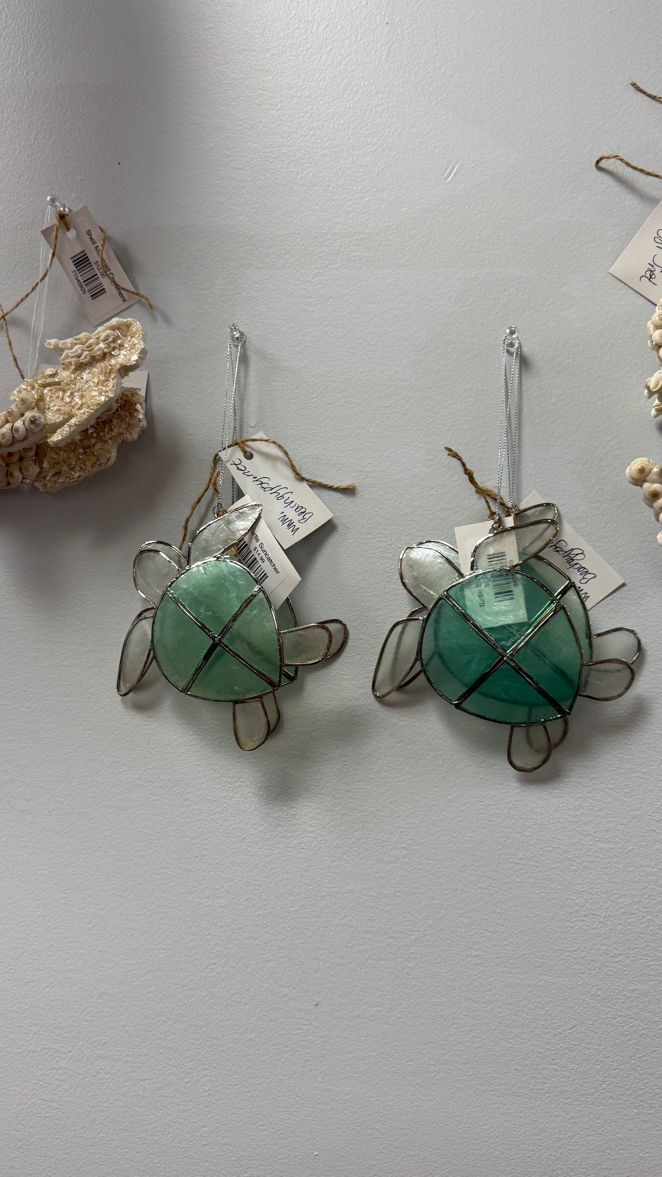 Two turtle-shaped decorations on a white surface with tags attached.
