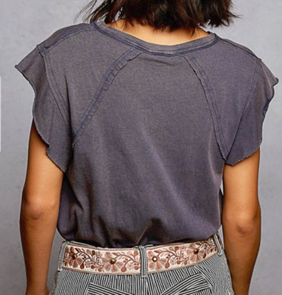 Person wearing a dark gray t-shirt with a floral belt against a plain background
