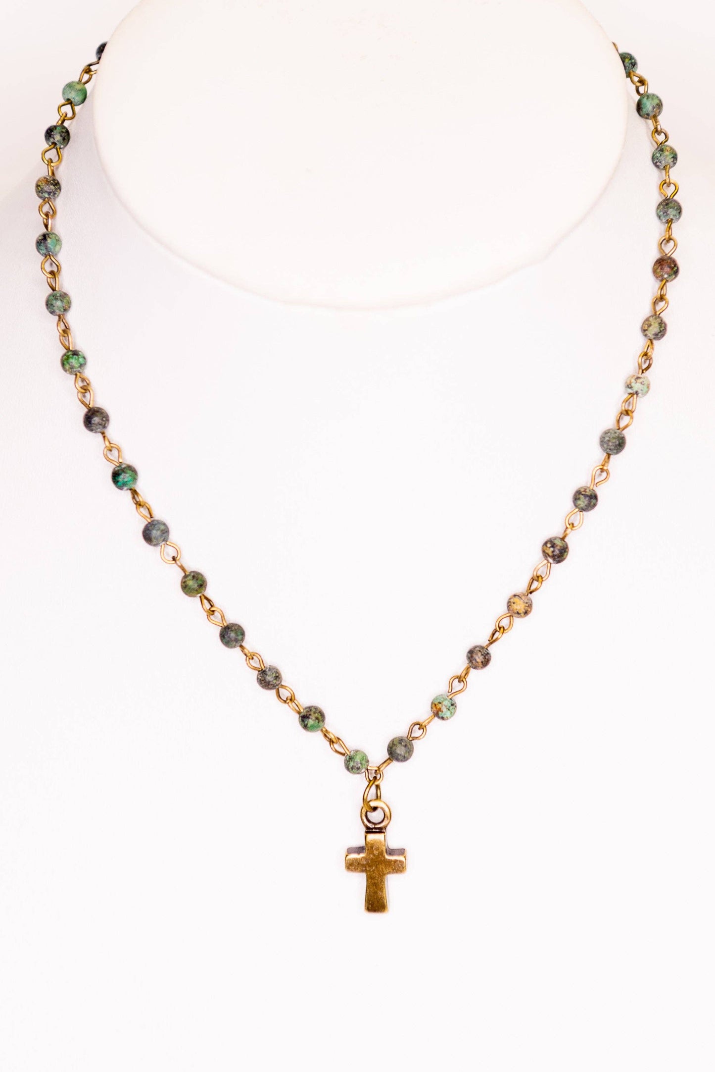 Necklace with green beads and a gold cross pendant on a white background