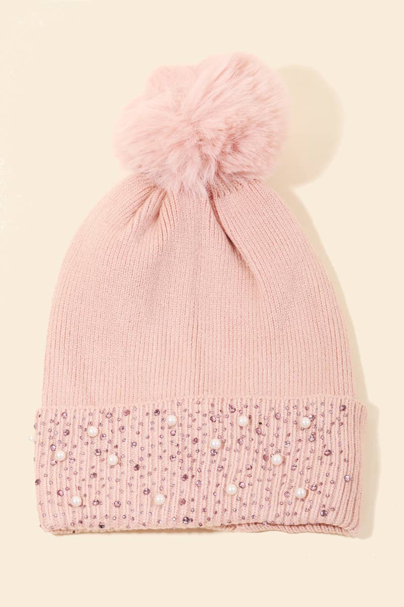Pink knit beanie with a pom-pom on a beige background