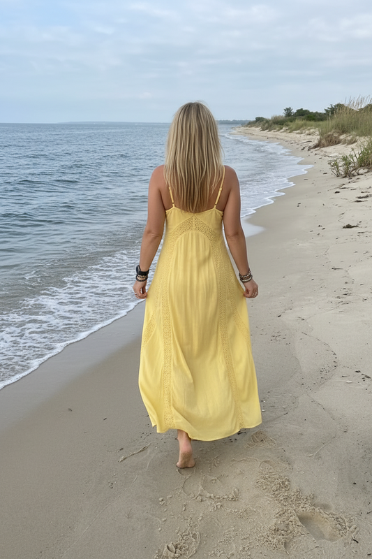Back view of Woman in a yellow dress walking on a beach