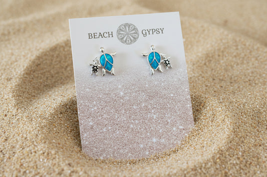 Turtle-shaped earrings on a 'Gypsy Beach' card with sand texture.