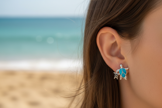 Close-up of a person wearing a turtle-shaped earring with a beach in the background