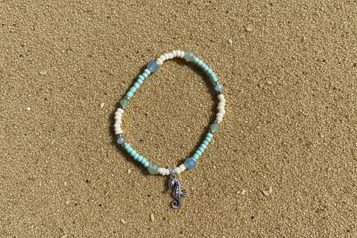 Beaded bracelet with a seahorse charm on a sand  background