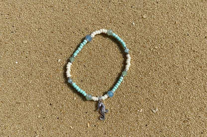 Beaded bracelet with a seahorse charm on a sand  background