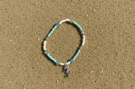 Beaded bracelet with a seahorse charm on a sand  background