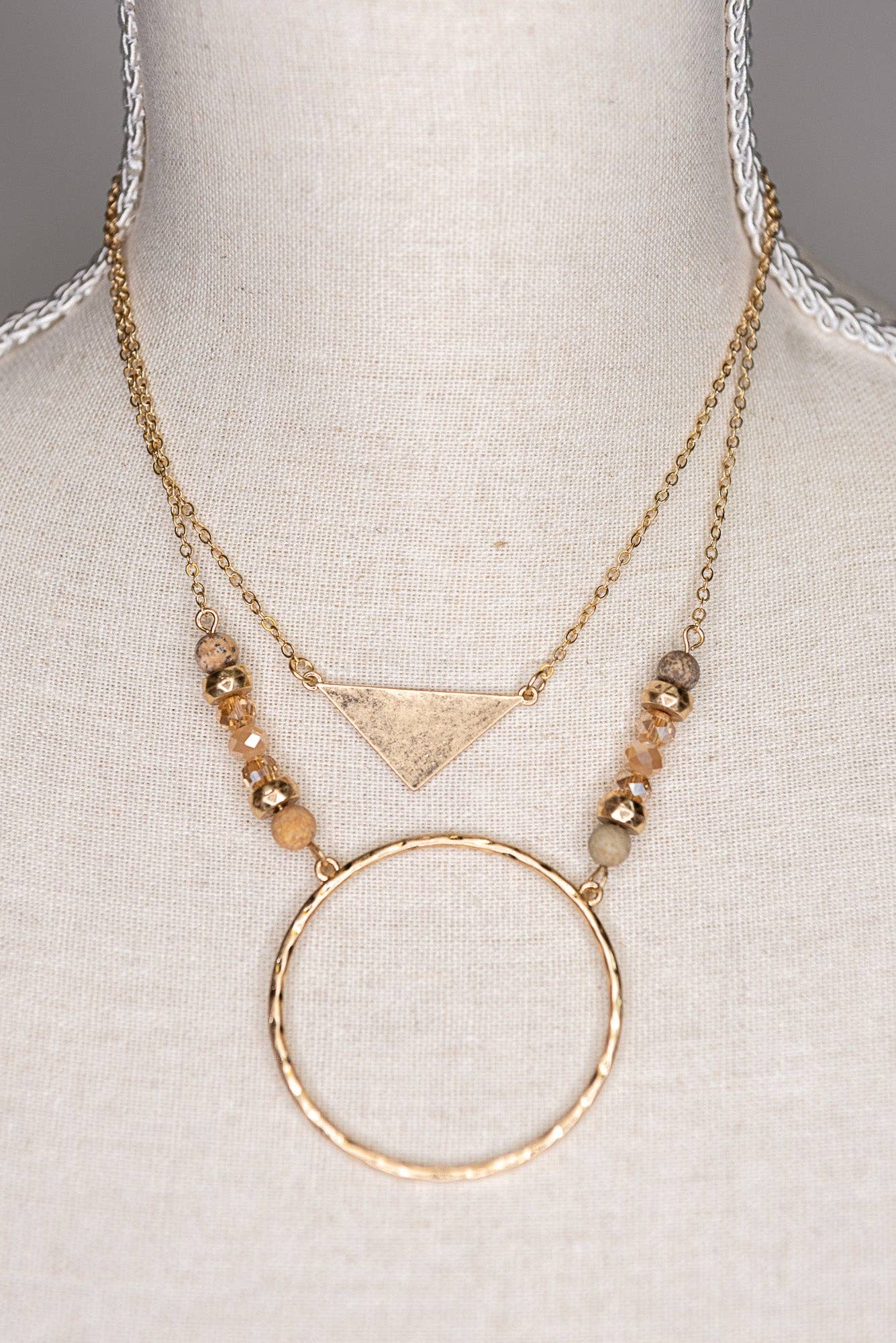 Gold necklace with geometric pendant on a mannequin bust