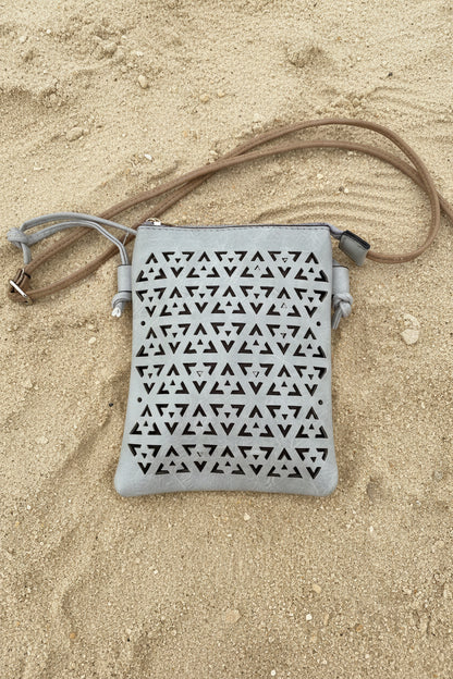 A light gray faux-leather shoulder bag with a geometric triangle cutout pattern, displayed on a bright pink background.