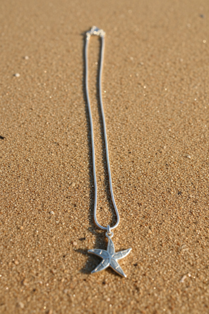 Starfish shaped pendant on a chain on a textured surface