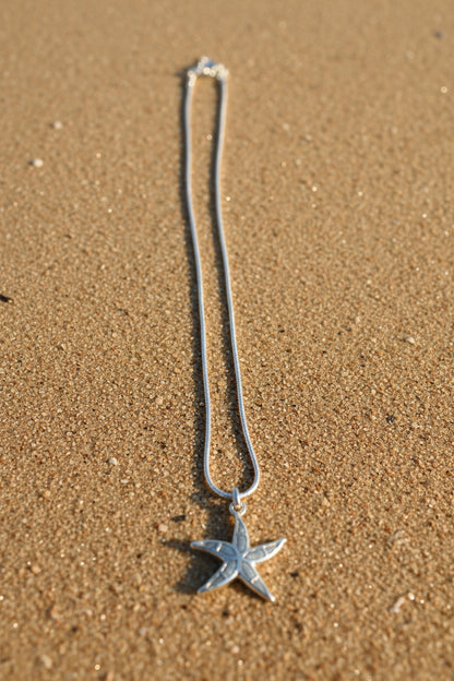 Starfish shaped pendant on a chain on a textured surface