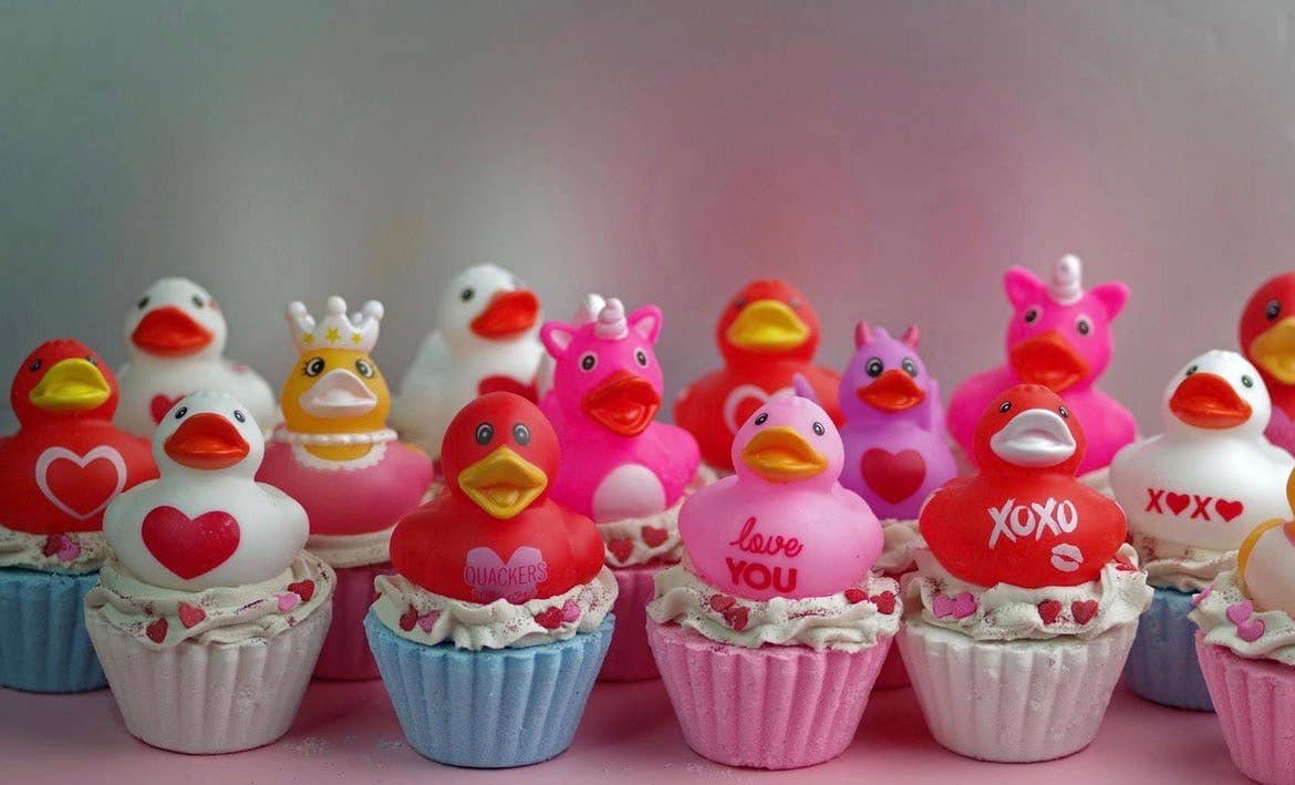 Row of small rubber ducks with decorative elements on a pink background