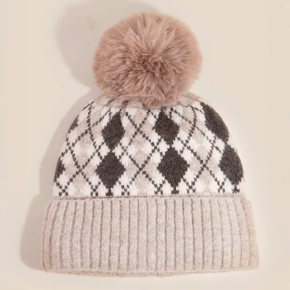 Knitted beanie with argyle pattern and fluffy pom-pom on a beige background