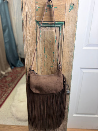 Brown Sueded Fringe Shoulder Bag with long fringe and shoulder strap, hanging on a rustic wood door – Beach Gypsy