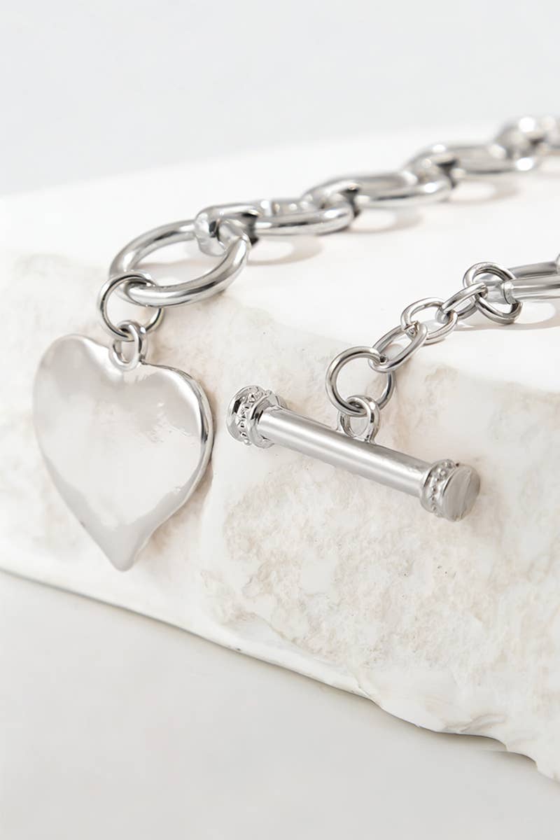 Silver bracelet with heart charm on a white background