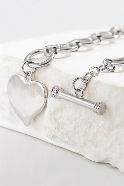 Silver bracelet with heart charm on a white background