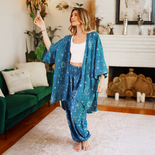 Woman in a blue patterned outfit burning sage in a living room.