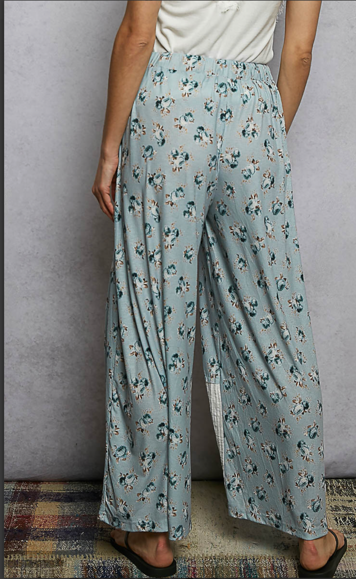 Back view of Woman wearing blue floral flowing pants with cream patches 