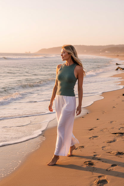 Woman wearing a ribbed green tank top against a beach background