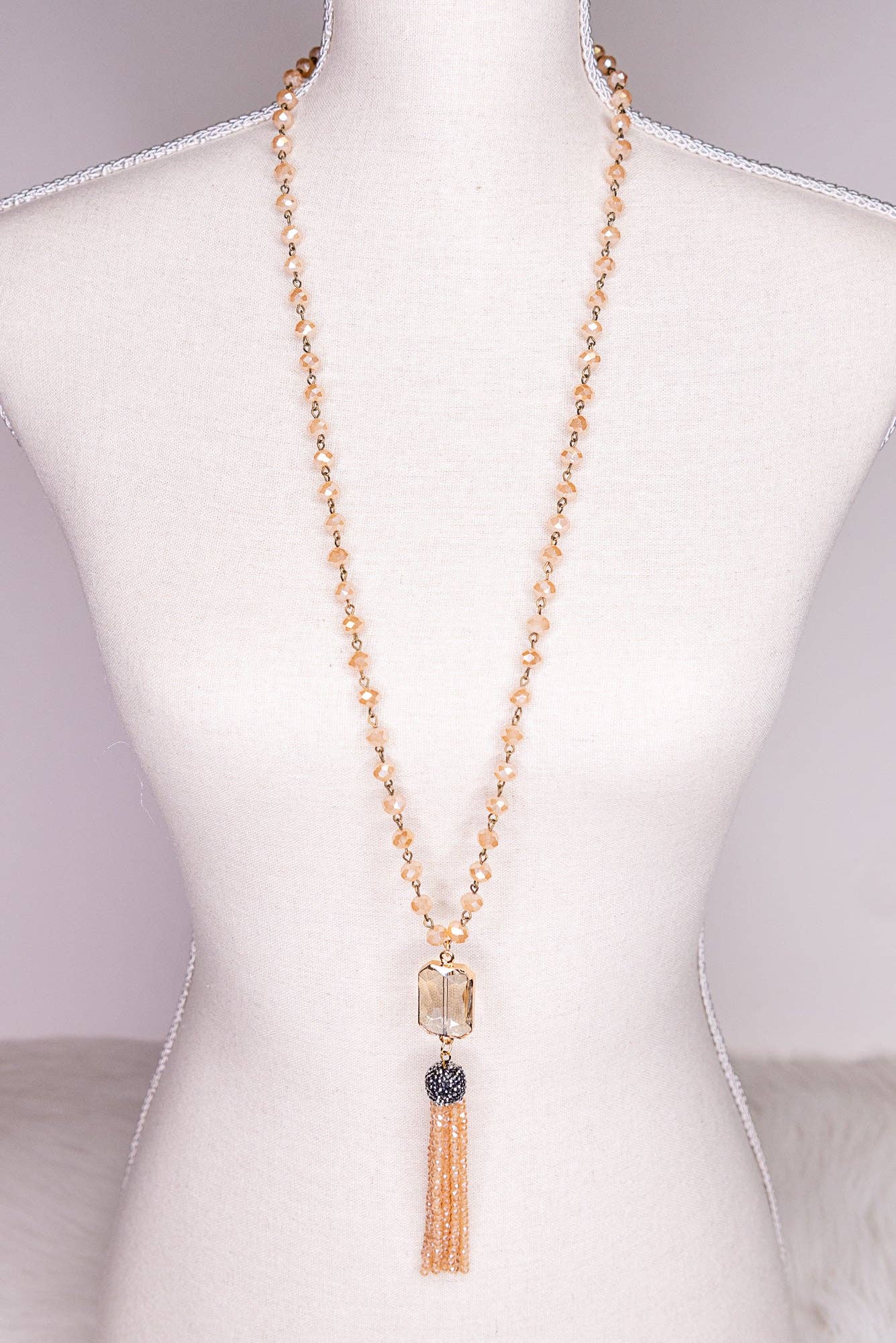 Necklace with tassel on a mannequin bust against a neutral background