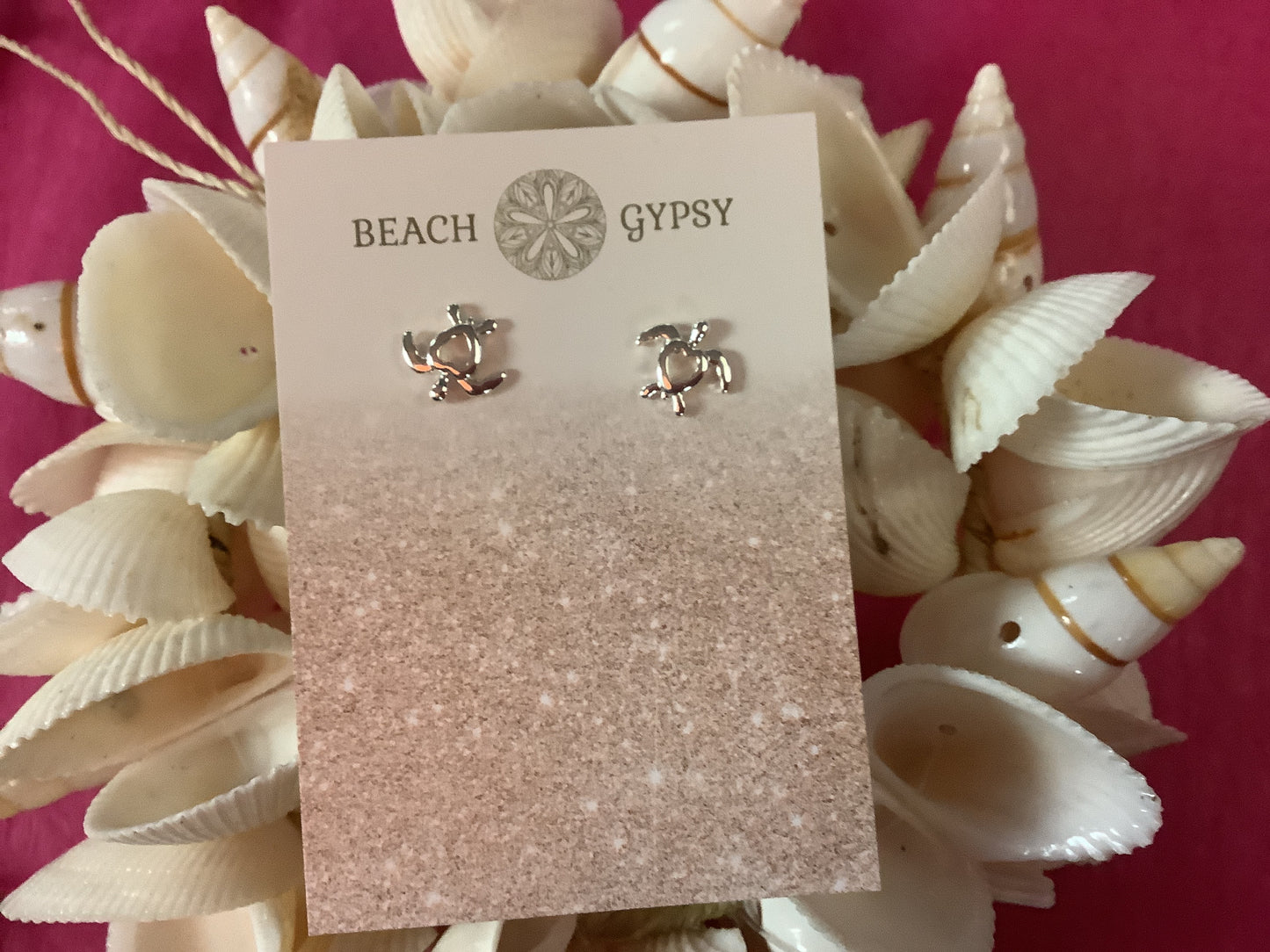 Silver earrings on a 'Beach Gypsy' branded card surrounded by seashells.