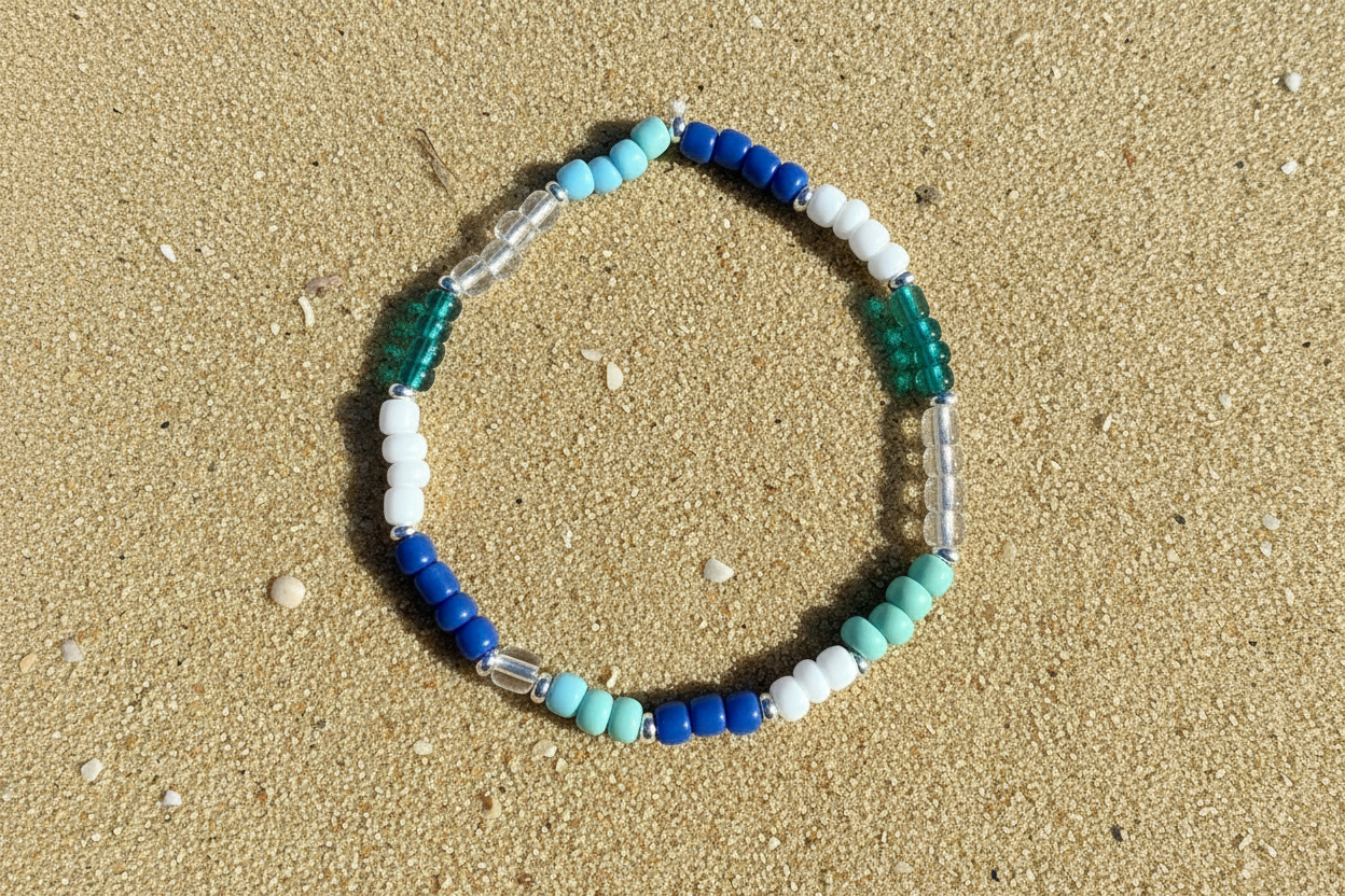 Beaded bracelet with multiple blue and white beads on sandy beach background 