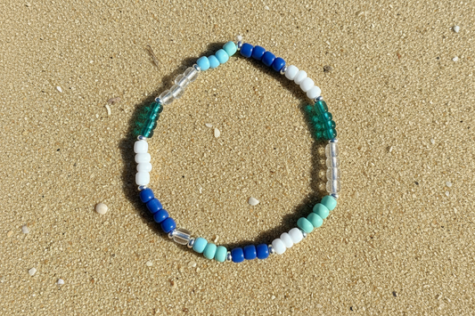 Beaded bracelet with multiple blue and white beads on sandy beach background 