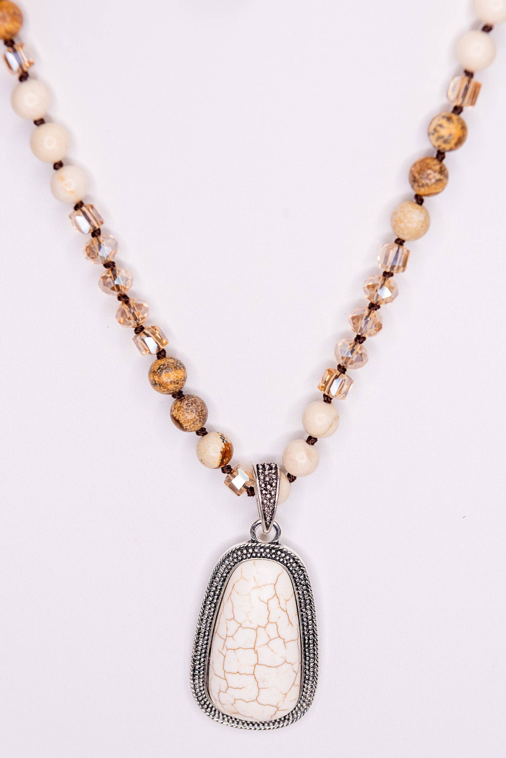 Necklace with a white pendant and beaded chain on a light background
