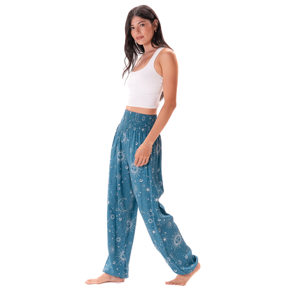 Woman wearing blue patterned pants and a white top on a white background Cosmic Sky Harem Pants in boho print — ultra-soft fabric with smocked waistband, handmade in Thailand
