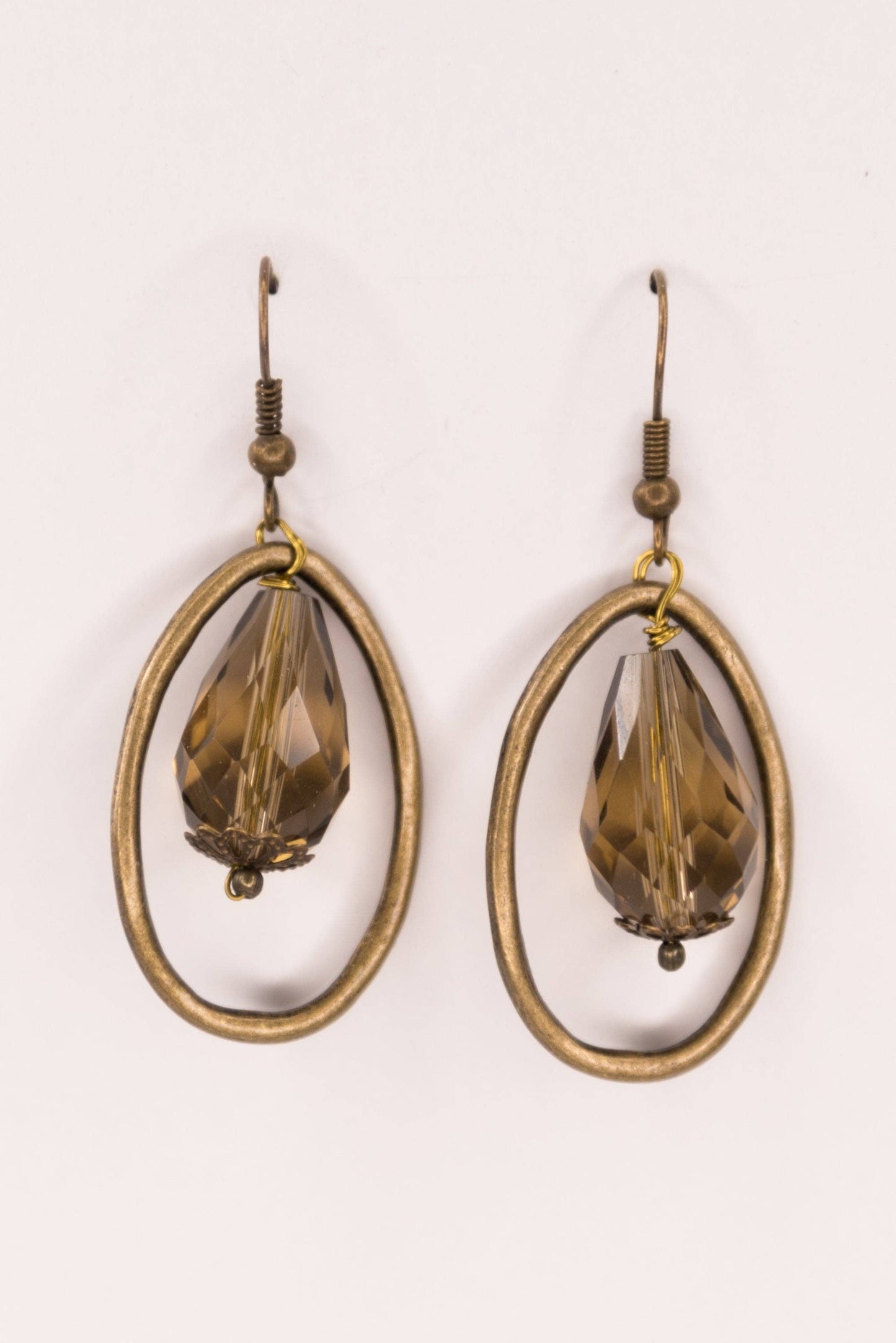 Pair of earrings with brown teardrop-shaped stones on a white background