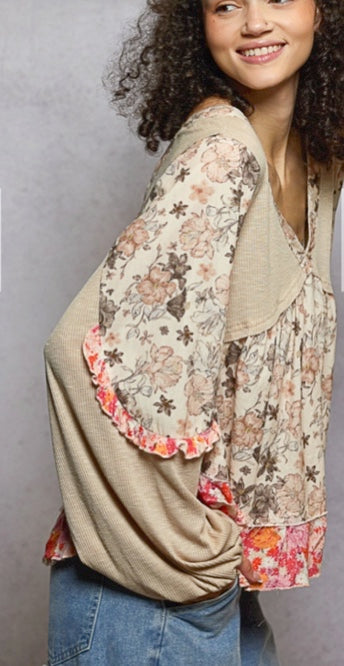 Woman wearing a floral and solid color top with a plain background