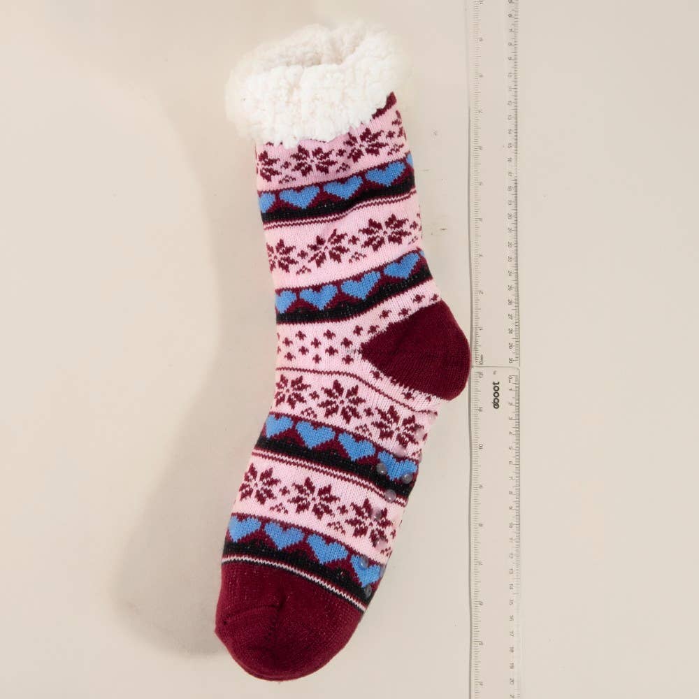 Knitted sock with colorful pattern next to a ruler on a beige background