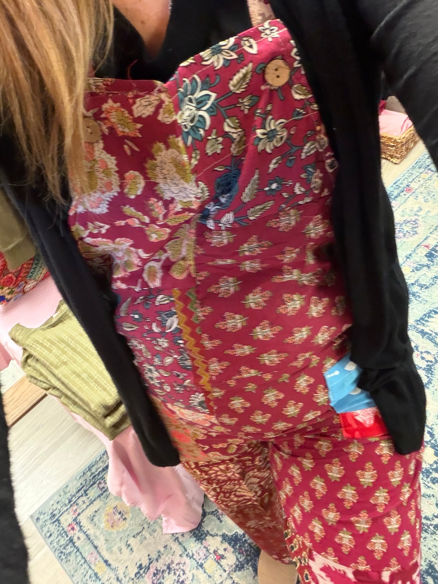 Person wearing a red floral patterned jumpsuit with a black jacket.