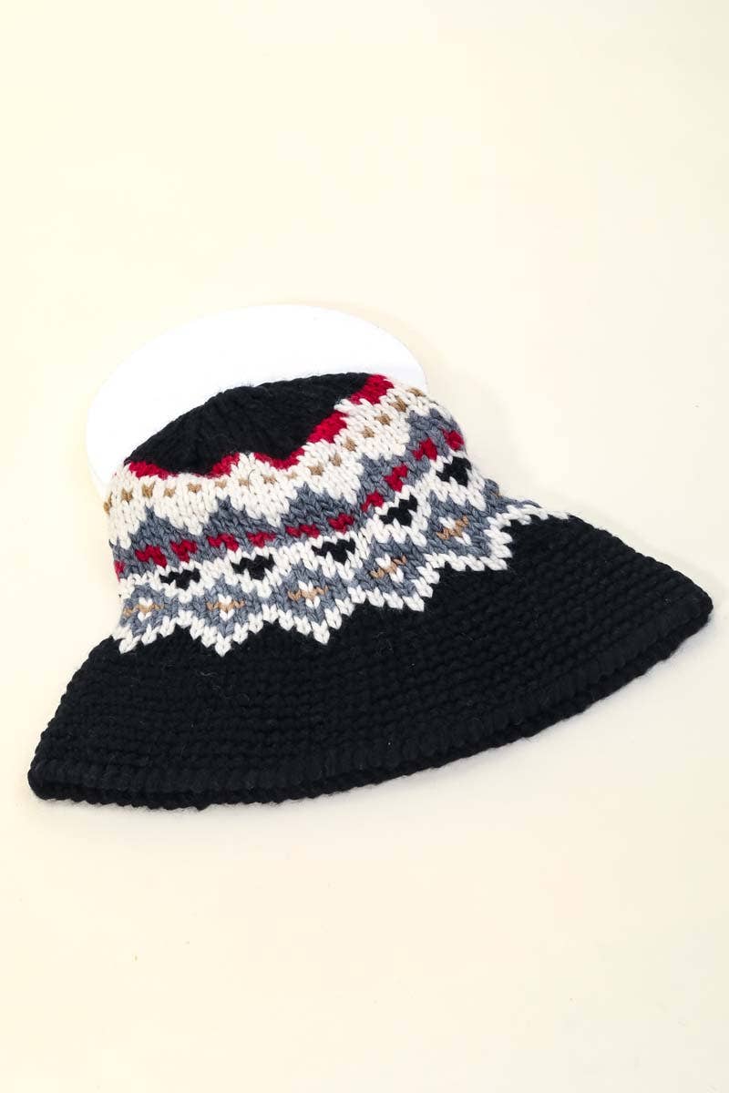 Knitted hat with a patterned top and solid black bottom on a beige background