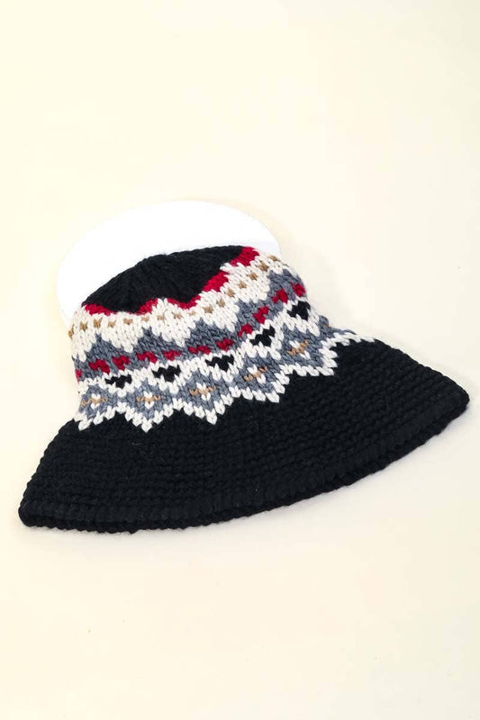 Knitted hat with a patterned top and solid black bottom on a beige background