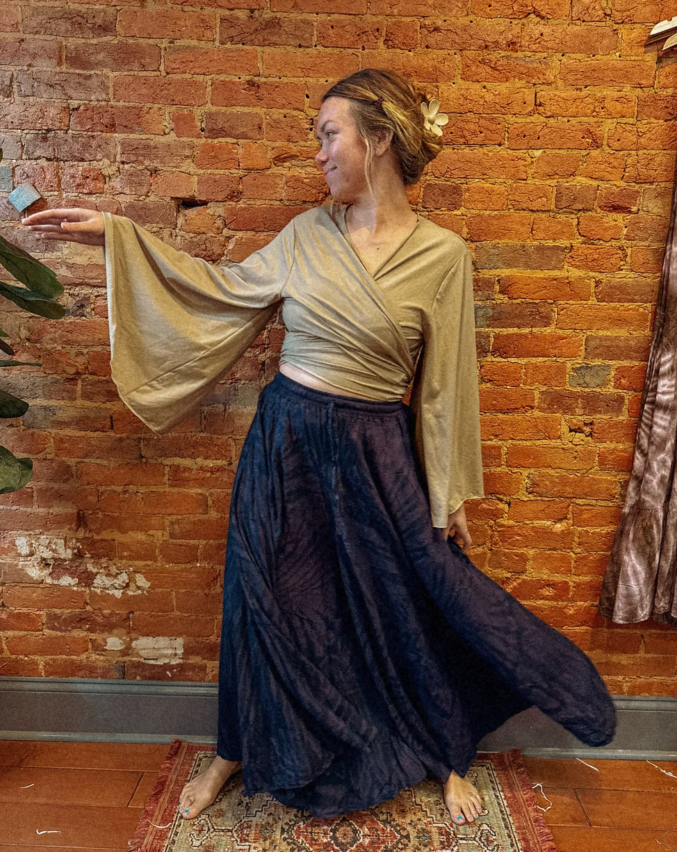 Woman in a flowing dress standing against a brick wall.