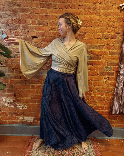 Woman in a flowing dress standing against a brick wall.