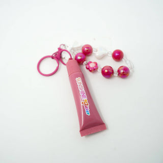 Pink lip gloss with a keychain and beads on a white background